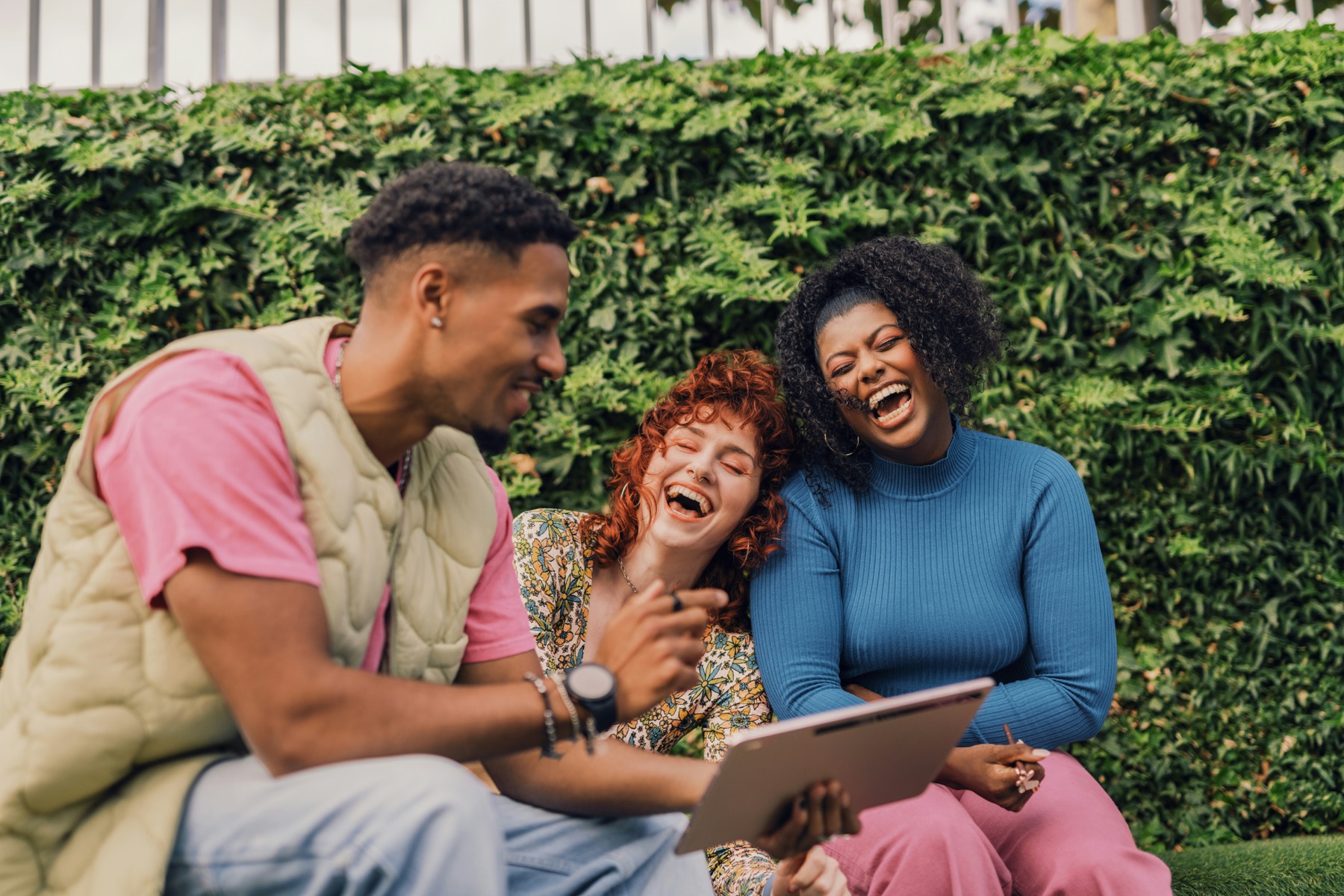 Three people laughing together while looking at a tablet